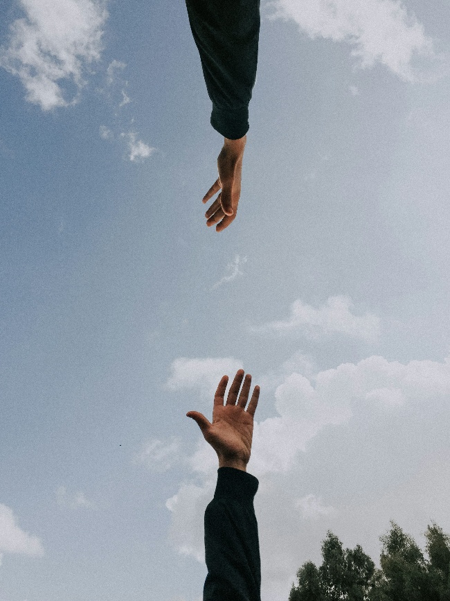 two hands reaching out to eachother, one from the top of the frame, another from the bottom of the frame