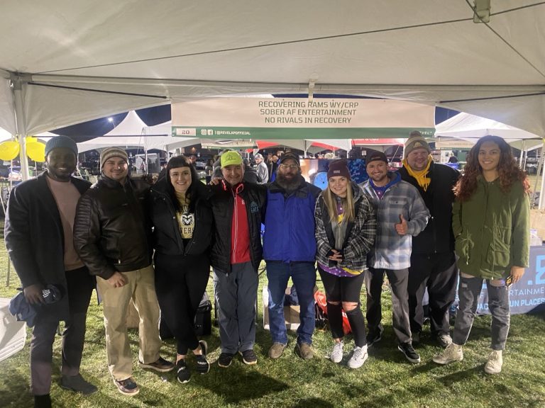 Group of Sober AF Entertainment volunteers and community members gathered under an event tent at night
